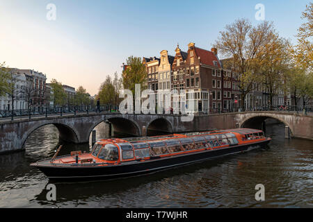 Brocca barca la navigazione sui canali si restringe di Amsterdam sotto la luce del tramonto, Amsterdam, Paesi Bassi Foto Stock