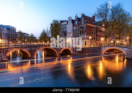 Esposizione lunga crociera in barca lungo la calma di Amsterdam canal al tramonto blu ora, Paesi Bassi Foto Stock