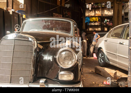 A cinquanta Mercedes Benz Ponton saloon sorge in un workshop garage in Mumbai, India, con giovani meccanica parlando in background. Foto Stock