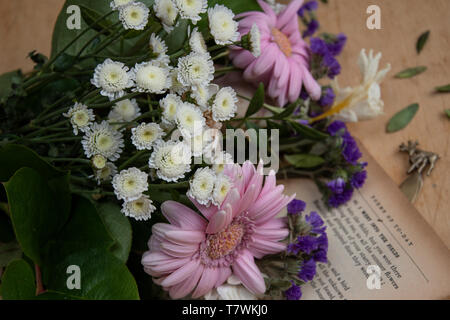 Un affievolimento bouquet di fiori si trova in un vecchio libro di poesie Foto Stock