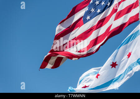 La bandiera comunale di Chicago e la bandiera americana al vento a Chicago contro il cielo blu chiaro Foto Stock