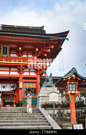 Una persona che fa una selfie pic in Fushimi Inari santuario. A sfondo: Fox tenendo un gioiello nella sua bocca al cancello principale del Fushimi Inari santuario. Foto Stock