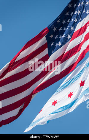 La bandiera comunale di Chicago e la bandiera americana al vento a Chicago contro il cielo blu chiaro Foto Stock