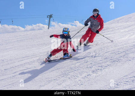 Ragazzo giovane sci con suo padre sulla buona pendenza preparato Foto Stock