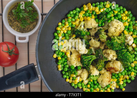 Le verdure su una padella. Cavolfiori, broccoli verdi piselli, mais, pomodori vicino, vista dall'alto Foto Stock