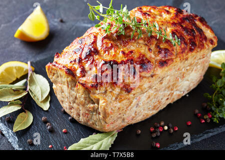 Delizioso pollo intero polpettone servito su un vassoio di ardesia con le fette di limone e di timo fresco su una tavola di cemento, vista orizzontale dal di sopra, close-up Foto Stock