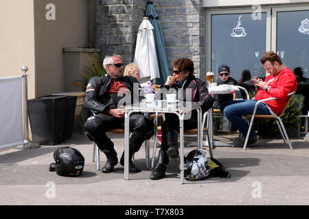 Lyme Regis, Dorset - Due bikers rivestiti in pelle in un caffè che prende una pausa caffè all'aperto, in stile al fresco, al sole Foto Stock