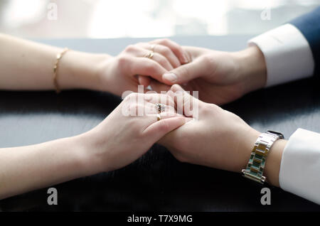Sposa e lo sposo tenere delicatamente le mani seduta al tavolo vicino fino Foto Stock