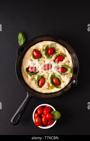 Concetto di alimentare la pasta in salita per vegan fatta in casa Focaccia organico nella padella padella di ferro su sfondo nero con spazio di copia Foto Stock