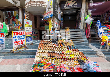 Scena di strada nel quartiere Mahipalpur, un sobborgo vicino all'Aeroporto di Delhi a Nuova Delhi, capitale dell India: locale uomo che lavora con un manuale di macchina per cucire Foto Stock