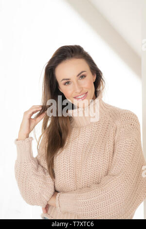 Donna sorridente in maglione beige Foto Stock