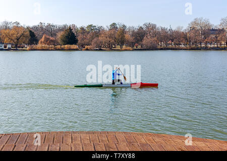 Nyiregyhaza, Ungheria- Febbraio 15, 2019: uomo canottaggio in canoa con pala , in piedi su un ginocchio. Treni atleta sul lago Foto Stock