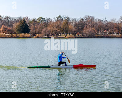 Nyiregyhaza, Ungheria- Febbraio 15, 2019: uomo canottaggio in canoa con pala , in piedi su un ginocchio. Treni atleta sul lago Foto Stock
