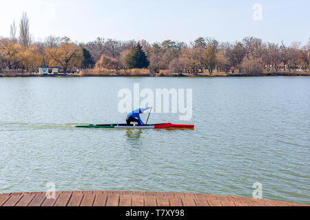 Nyiregyhaza, Ungheria- Febbraio 15, 2019: uomo canottaggio in canoa con pala , in piedi su un ginocchio. Treni atleta sul lago Foto Stock