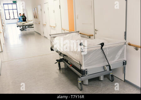 Un bianco coperto letto vuoto su un pavimento di ospedale. Foto Stock