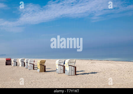 Dal tetto di numerose sedie da spiaggia in vimini su una deserta spiaggia di sabbia sotto il cielo azzurro in Germania Foto Stock