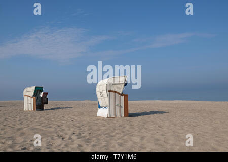 Dal tetto di due sedie da spiaggia in vimini sotto il cielo blu su una deserta spiaggia sabbiosa del Mar Baltico in Germania Foto Stock