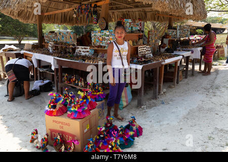 America centrale del mercato e di stallo donna adolescente commerciante vendita di bambole e di altri oggetti di artigianato; Tikal, Guatemala America Latina Foto Stock