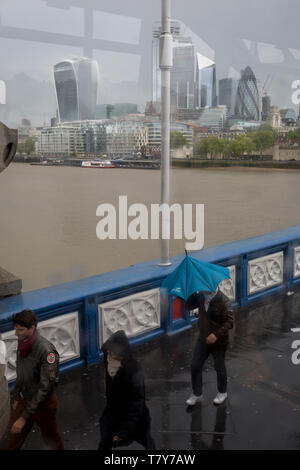 I turisti coraggiosi un umido e ventoso il Tower Bridge e il Tower Bridge, del 8 maggio 2019, a Londra, in Inghilterra. Foto Stock