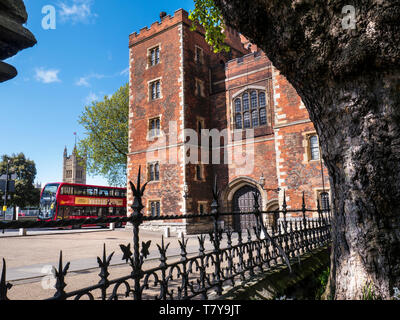 Lambeth Palace di Londra. Morton's Tower con il Parlamento e il rosso London bus. Mattone rosso Tudor gatehouse formante l'ingresso al Lambeth Palace London REGNO UNITO Foto Stock