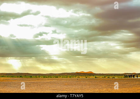 Il lago in Marocco all'alba ai piedi del deserto del Sahara. Il sole splende attraverso le nuvole. Nel telaio della macchina e un gruppo di turisti che Foto Stock