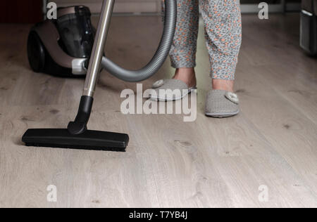 I lavori domestici e il servizio di pulizie concetto. La donna aspira il pavimento in laminato con spessore della pila. Spazio di copia Foto Stock