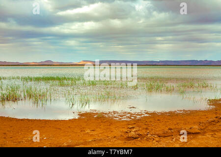 Il lago in Marocco all'alba ai piedi del deserto del Sahara. Il sole splende attraverso le nuvole. Foto Stock