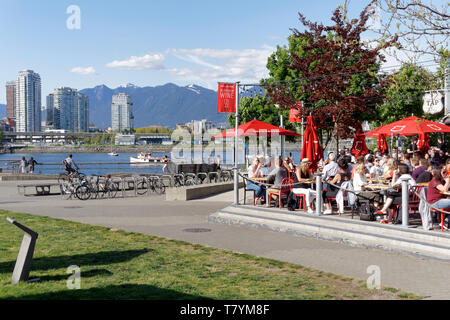 La Gente seduta sul lungomare patio esterno del rubinetto e canna Ristorante nel villaggio olimpico su False Creek, Vancouver, BC, Canada Foto Stock