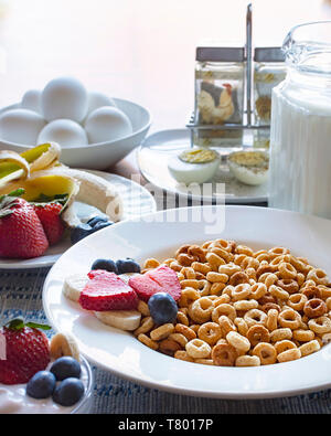 Una ciotola di cereali di avena con frutta, latte, uova e yogurt come parte di una colazione bilanciata. Foto Stock