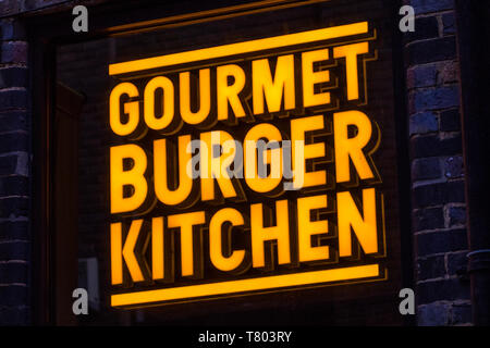 London, Regno Unito - 1 Aprile 2019: Il logo della società di Gourmet Burger Kitchen sopra l'entrata di uno dei loro ristoranti in Londra, Regno Unito. Foto Stock