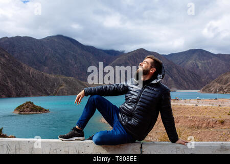 L'uomo nei primi anni quaranta tardi anni trenta per godersi il sole in diga Potrerillos, Mendoza, Argentina Foto Stock