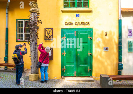 Sibiu, Romania - 22 Aprile 2019: Senior turista giovane di fotografare il pilastro Journeymen, un unico, vecchio palo di legno con chiodi in esso a Casa C Foto Stock