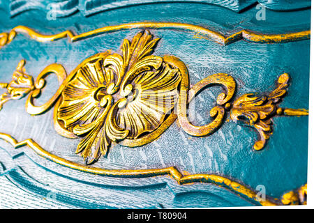 Dettagli floreali su una cassa di legno, in stile antico. Close up di sculture giallo su splendidamente scolpito arredamento blu sullo sfondo. Foto Stock