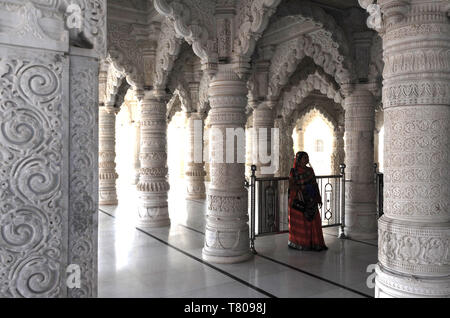 Donna indù in rosso sari all'interno riccamente decorata in marmo bianco Swaminarayan tempio, costruito dopo il terremoto del 2001, Bhuj, Gujarat, India, Asia Foto Stock