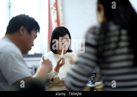 (190510) -- HARBIN, 10 maggio 2019 (Xinhua) -- Tingting Qin (C) ha il pranzo con i suoi genitori a loro residenza a Harbin, a nord-est della Cina di Heilongjiang Provincia, in data 9 maggio 2019. Qin Tingting, originariamente dalla Cina del nord della Mongolia Interna Regione Autonoma, è una matricola di Harbin università di ingegneria. La sofferenza da Myasthenic congenita sindrome (CMS, noto anche come debolezza muscolare), ella ha a sedersi su una sedia a rotelle e rendere molto più sforzo rispetto alla media di persone. Dopo aver diagnosticato con CMS, Qin non ha mai dato il suo sogno che voleva entrare in università. Ella è stata ammessa al collegio di M Foto Stock