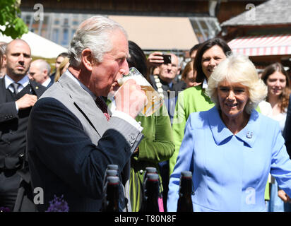 Glonn, Germania. Il 10 maggio, 2019. Charles, Principe di Galles, visiti la fattoria organica Herrmannsdorfer Landwerkstätten e bevande a partire da un vetro accanto alla moglie Camilla, duchessa di Cornovaglia. Dietro di lei è Ilse Aigner (CSU). Credito: Matthias esitano di fronte/Piscina dpa/dpa/Alamy Live News Foto Stock