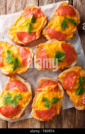 Aprire cotto toast pizza con salame salsiccia e formaggio fuso formaggio cheddar vicino sul tavolo. Verticale in alto vista da sopra Foto Stock