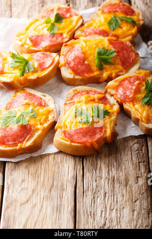 Deliziosi toast aperti con salame salsiccia e formaggio fuso formaggio cheddar vicino sul piano verticale. Foto Stock