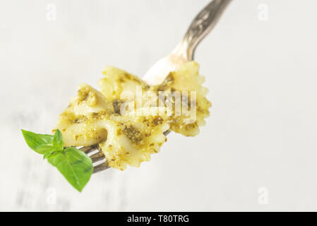 Pezzo di farfalle di pasta al pesto e di foglie di basilico fresco su una forcella Foto Stock