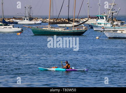 Un uomo va in kayak nel vecchio pontile del pescatore di Monterey, CA (3 agosto 2018) Foto Stock