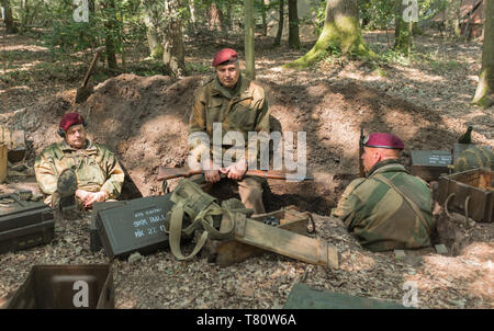 Woodhall Spa 1940s guerra mondiale due festival rievocazione weekend. Tre i paracadutisti in seduta una foxhole circondato da boschi e scatole di munizioni Foto Stock
