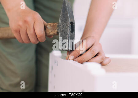 Donna carpenter colpendo chiodo con un martello. Close up. Foto Stock