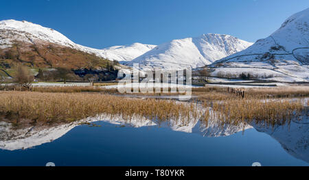 Soleggiato Snowclad fells intorno Hartstop riflessa nei fratelli acqua, Parco Nazionale del Distretto dei Laghi, Sito Patrimonio Mondiale dell'UNESCO, Cumbria, England, Regno Unito Foto Stock