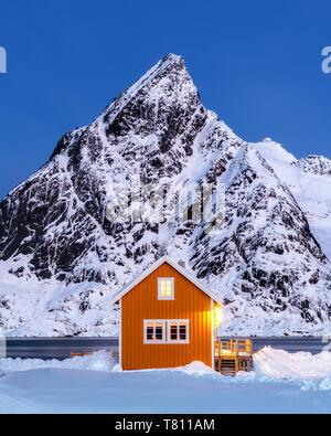 Giallo capanna rorbuer nella neve al crepuscolo, Sakrisoy nei, Moskenesoya, Isole Lofoten, Nordland, Norvegia, Europa Foto Stock