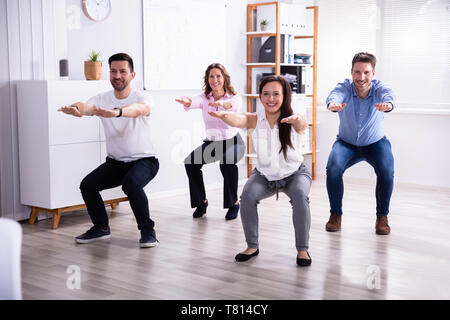 Sorridente Giovani Imprenditori facendo sit ups in Office Foto Stock