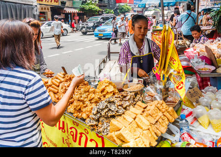 Bangkok, Tailandia - 21 Aprile 2011: il cliente acquistare spuntini da un cibo di strada fornitore. Chinatown è piena di carrelli di cibo. Foto Stock