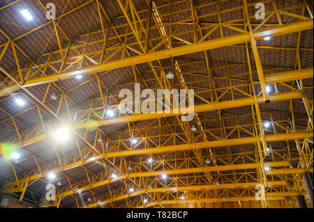 Metallo giallo struttura sul tetto con illuminazione a lampada in magazzino Foto Stock