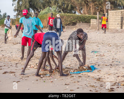 Il Senegal, Africa - 26 Gennaio 2019: giovani ragazzi africani sono la pulizia della spiaggia dall'inquinamento a giocare a calcio. Concetto di inquinamento. Fisher colorati Foto Stock