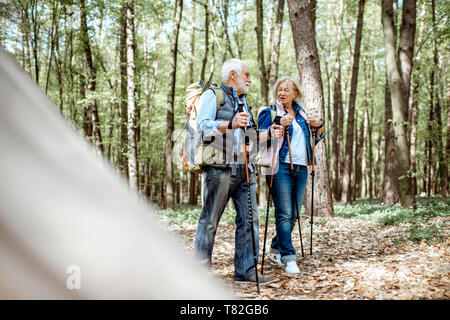 Bella coppia senior escursionismo con zaini e bastoncini da trekking nella foresta. Concetto di stile di vita attivo su pensionamento Foto Stock