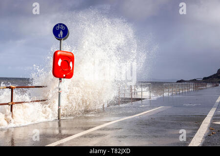 Salvagente su Colwyn Bay lungomare con le onde che si infrangono in una tempesta Foto Stock